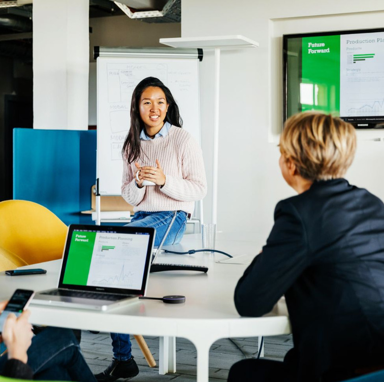 Two women collaborating at work while using Crestron AirMedia dongle